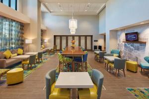 Hampton Inn & Suites Sacramento at CSUS في سكرامنتو: غرفة طعام بها طاولات وكراسي وبهو