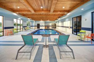 pokój przy basenie z krzesłami i stołem oraz basen w obiekcie Home2 Suites By Hilton Oklahoma City Airport w mieście Oklahoma City