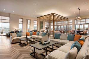 a living room with couches and tables and windows at Embassy Suites By Hilton San Antonio Landmark in San Antonio