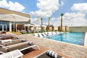 una piscina en un hotel con tumbonas y sombrilla en Embassy Suites By Hilton San Antonio Landmark, en San Antonio