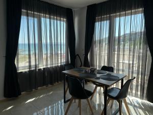 a dining room with a table and chairs and large windows at First Line On The Beach Cosy Sea Paradise Apartments in Kavarna
