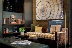 a living room with a couch and a shelf of books at The Porter Portland, Curio Collection By Hilton in Portland