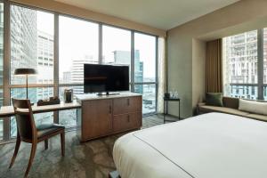 a hotel room with a bed and a desk with a television at The Porter Portland, Curio Collection By Hilton in Portland