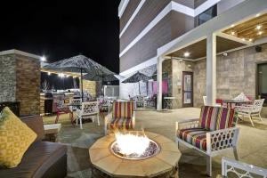 a patio with a fire pit and chairs and tables at Home2 Suites by Hilton KCI Airport in Kansas City