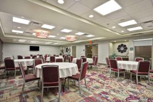 a conference room with tables and chairs and a screen at Home2 Suites by Hilton KCI Airport in Kansas City