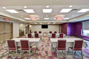 uma sala de conferências com mesas e cadeiras brancas e um ecrã em Home2 Suites by Hilton KCI Airport em Kansas City