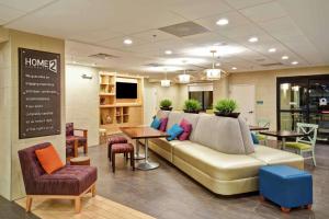 a waiting room with a couch and tables and chairs at Home2 Suites by Hilton Atlanta Norcross in Norcross