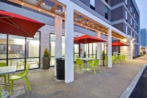 a patio with tables and chairs and red umbrellas at Home2 Suites By Hilton Columbus Airport East Broad in Columbus