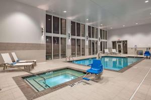 a swimming pool with a blue chair in a building at Hilton Garden Inn Dallas At Hurst Conference Center in Hurst