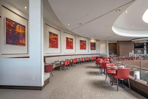 a dining room with red chairs and tables at Hilton Garden Inn Dallas At Hurst Conference Center in Hurst