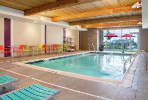 a pool in a hotel with chairs and a table at Home2 Suites By Hilton Indianapolis Greenwood in Indianapolis