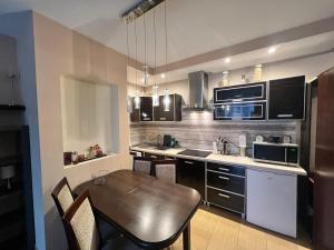 a kitchen with a wooden table and a kitchen with appliances at Apartament Nuldenovski Resort Grzybowo in Grzybowo