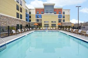 a swimming pool with chairs and a building at Homewood Suites By Hilton Rocky Mount in Rocky Mount