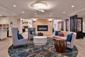 a lobby with chairs and a couch and a table at Homewood Suites Des Moines Airport in Des Moines