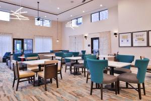 a dining room with tables and chairs and windows at Homewood Suites Des Moines Airport in Des Moines