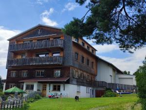 a large building with a dog standing in front of it at Stockreutehof in Sulzberg