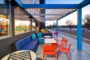 une terrasse avec un canapé bleu, des tables et des chaises dans l'établissement Tru By Hilton Salt Lake City Airport, à Salt Lake City