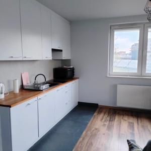 a kitchen with white cabinets and a sink and a window at Pszczelna Loft in Kraków