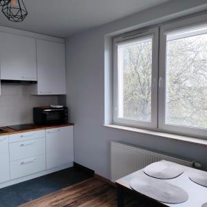 a kitchen with white cabinets and a table and two windows at Pszczelna Loft in Kraków