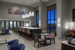 un restaurant avec un bar, des tables et des chaises dans l'établissement Hampton Inn & Suites Chicago-Burr Ridge, à Burr Ridge