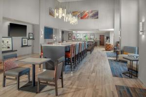 a restaurant with a bar and tables and chairs at Hampton Inn & Suites Chicago-Burr Ridge in Burr Ridge
