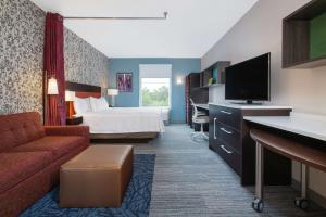 a hotel room with a bed and a flat screen tv at Home2 Suites Smithfield Providence in Smithfield