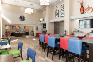 a dining room with a long bar with colorful chairs at Hampton Inn & Suites Lafayette in Lafayette