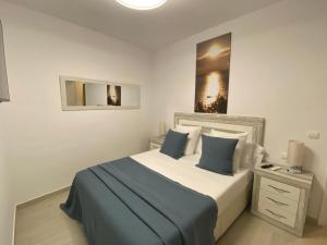 a bedroom with a large bed with blue and white pillows at Apartaments L’ARC in Palafrugell