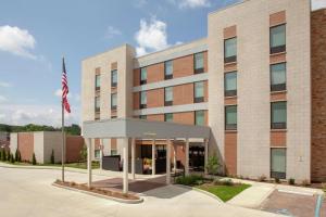 un edificio de oficinas con una bandera americana delante en Home2 Suites by Hilton Bloomington, en Bloomington