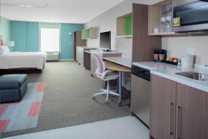 a hotel room with a kitchen and a bedroom at Home2 Suites by Hilton Bloomington in Bloomington