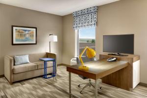 a living room with a couch and a desk with a television at Hampton Inn & Suites Rexburg in Rexburg