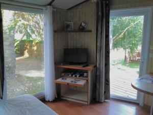 1 dormitorio con TV y puerta corredera de cristal en PARADISE CHALLETS AND CAMPING, en Sarrecave