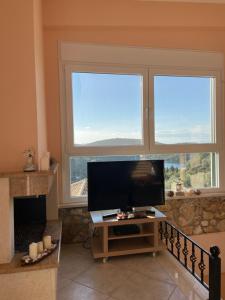 a living room with two windows and a flat screen tv at Elena's House in Syvota