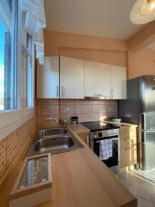 uma cozinha com armários brancos e um lavatório de aço inoxidável em Elena's House em Sivota