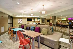a waiting room with a couch and tables and chairs at Home2 Suites Mechanicsburg in Mechanicsburg