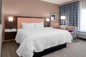 StanleyHampton Inn & Suites Overland Park South的配有一张大床和一把椅子的酒店房间