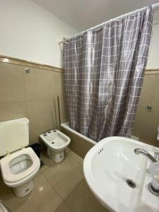 a bathroom with a toilet and a sink and a shower curtain at Departamento Centro in Santiago del Estero