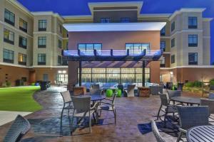 a patio with tables and chairs in front of a building at Homewood Suites By Hilton Savannah Airport in Savannah