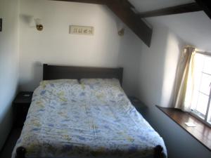 a bedroom with a bed with a blue comforter and two windows at Barton Cottage in Bude