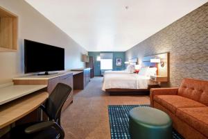 Home2 Suites by Hilton Victorville في فيكتورفيل: غرفة فندقية بسرير وتلفزيون بشاشة مسطحة