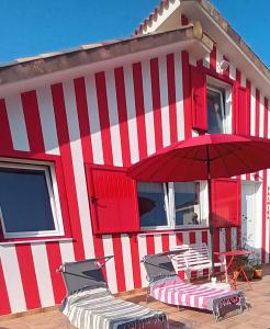 a red and white building with a table and an umbrella at Casiña Palmira in Finisterre