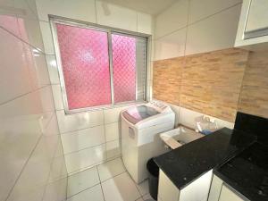 baño pequeño con lavadora y ventana en Apartamento Top, en Balneário Camboriú
