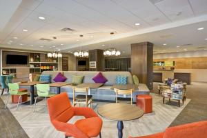 eine Lobby mit einem Sofa, Tischen und Stühlen in der Unterkunft Home2 Suites By Hilton Plymouth Minneapolis in Plymouth