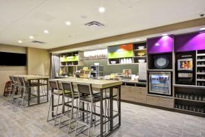 a restaurant with bar stools and a food counter at Home2 Suites By Hilton Plymouth Minneapolis in Plymouth