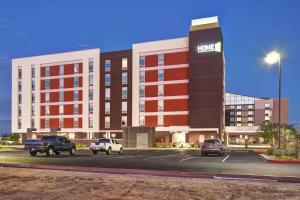 吉尔伯特Home2 Suites by Hilton Gilbert的一座大楼，停车场里停满了汽车
