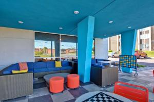 una hall con divano blu e sedie arancioni di Tru by Hilton Syracuse North Airport Area a Liverpool