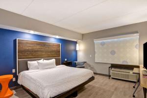 1 dormitorio con cama y pared azul en Tru by Hilton Syracuse North Airport Area, en Liverpool