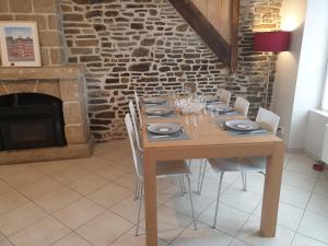 uma mesa de madeira com cadeiras e uma lareira de pedra em Maison de ville située à 8 kms du Mont St Michel em Pontorson