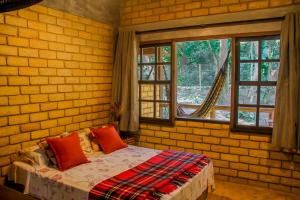 um quarto com paredes de tijolo, uma cama e uma janela em Chalé 03 Itaipu Vale da Colina Niterói em Niterói