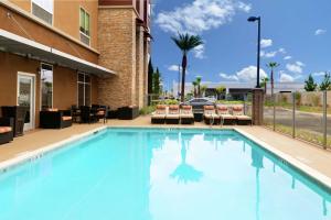 a large swimming pool with chairs and a building at Hampton Inn & Suites Buena Park in Buena Park